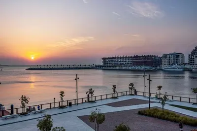 a sunset over a body of water with palm trees at Coastal Hideaway in La Mer - Beach Access and Burj View in Dubai