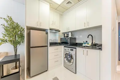 a kitchen with white cabinets and a washer and dryer at Charming Studio, Easy Access to Beach - Botanica Tower, Dubai Marina by Deluxe Holiday Homes in Dubai