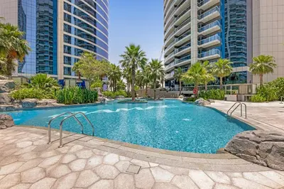 a swimming pool with palm trees and tall buildings at Burj Khalifa View - Luxurious 1BHK in Business Bay in Dubai