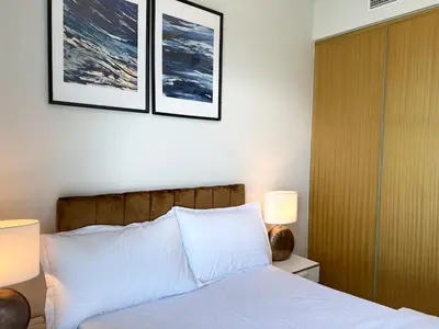 a bedroom with a bed with two pictures on the wall at Cozy 2BHK - Sea View in Dubai