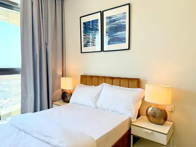 a bedroom with a bed with two lamps and a window at Cozy 2BHK - Sea View in Dubai