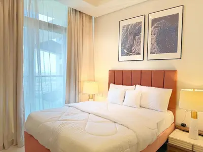 a bedroom with a bed with two lamps and a window at Cozy 2BHK - Sea View in Dubai