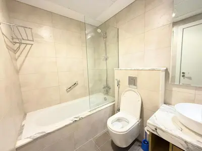 a bathroom with a toilet and a tub and a sink at Cozy 2BHK - Sea View in Dubai