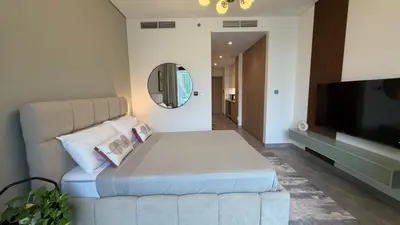 a bedroom with a large bed and a flat screen tv at Stylish Studio Apartment in Peninsula 1 in Dubai
