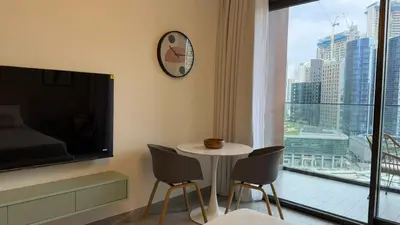a room with a table and chairs and a large window at Stylish Studio Apartment in Peninsula 1 in Dubai
