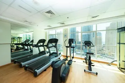 a gym with tread machines and a large window at Superb Marina Views, Entire 1BR Apartment - Atlantic Towers next to Marina Mall in Dubai