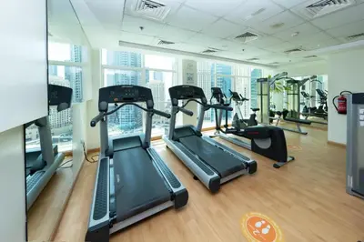 a gym with treadmills and ellipticals in a building at Superb Marina Views, Entire 1BR Apartment - Atlantic Towers next to Marina Mall in Dubai