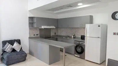 a kitchen with a refrigerator and a table and a chair at Superb Marina Views, Entire 1BR Apartment - Atlantic Towers next to Marina Mall in Dubai