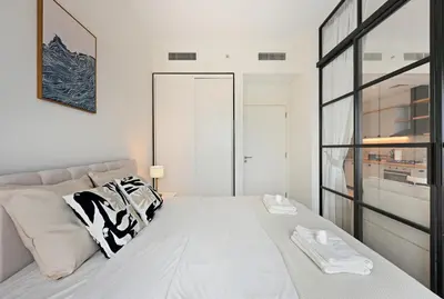 a white bedroom with a large bed and a window at Socio Tower Apt - Parking, Balcony&Pool - by Rentujemy in Dubai