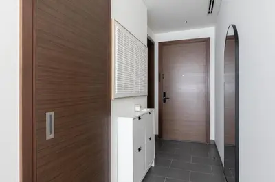a hallway with a wooden door and a bathroom at Cosy Sobha Hartland Apt - Pool&Gym - Near Downtown in Dubai