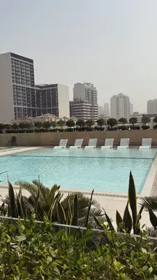 a swimming pool with lounge chairs in a city at Cozy and Stylish 1BR in JVC in Dubai