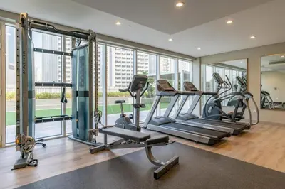 a gym with treadmills and ellipticals in a room with windows at Canal View Retreat in Business Bay in Dubai