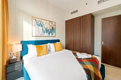 a bedroom with a large white bed with orange pillows at Fireworks Burj Khalifa View - One bedroom Apartment in Dubai