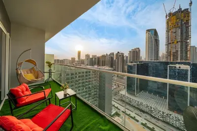 a balcony with red chairs and a view of a city at Fireworks Burj Khalifa View - One bedroom Apartment in Dubai