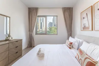 a white bedroom with a large bed and a window at HAVN - 3 Bedroom in Downtown, Burj Khalifa View in Dubai