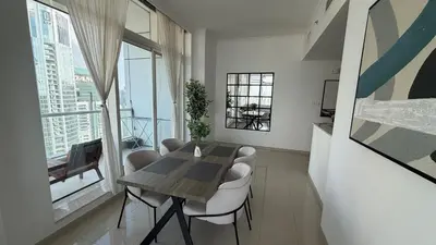 a dining room with a table and some white chairs at Stunning 1-Bedroom Apartment in Botanica Tower in Dubai