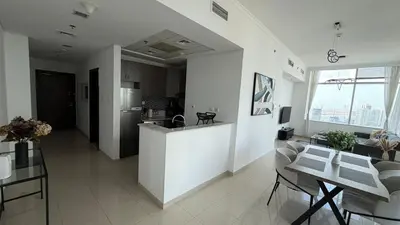 a kitchen and a living room with a counter and a table at Stunning 1-Bedroom Apartment in Botanica Tower in Dubai