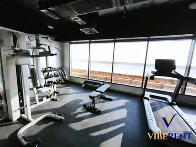 a gym with treadmills and chairs in a room with windows at 2BHK near Expo, Al Maktoum Airport, Rooftop Pool in Dubai