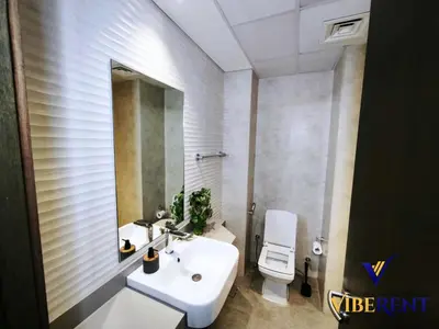 a bathroom with a sink and a toilet and a mirror at 2BHK near Expo, Al Maktoum Airport, Rooftop Pool in Dubai