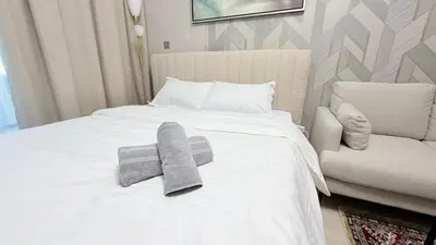 a bed with two towels on it with a chair at Luxure Studio with Pool View in Dubai