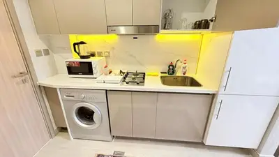a small kitchen with a sink and a washing machine at Luxure Studio with Pool View in Dubai