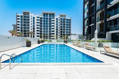 a swimming pool with chairs and buildings in the background at Luxury Studio in the Heart of Meydan in Dubai