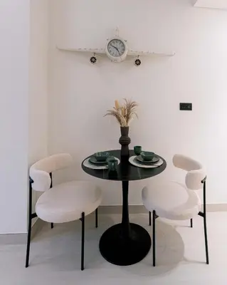 a black table with white chairs and a clock on the wall at Stylish central apartment, own Jaccuzi, burj view in Dubai
