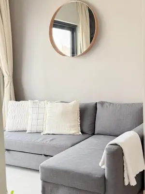a living room with a gray couch and a mirror at 4 Person - Resort Canal View - CBD Parking Pool in Dubai