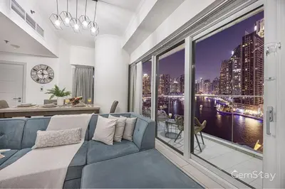 a bedroom with a blue couch and a large window at Beautiful Marina Skyline Serenity Spacious n Bright in Dubai
