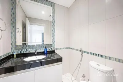 a white bathroom with a sink and a mirror at Beautiful Marina Skyline Serenity Spacious n Bright in Dubai