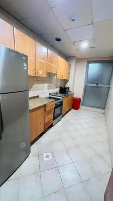 a kitchen with wooden cabinets and a stainless steel refrigerator at Velvet Vault Partition Room In Barsha Heights Tecom in Dubai