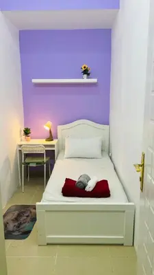 a bedroom with a white bed with a purple wall at City Stay Partition Room in Barsha Heights tecom in Dubai