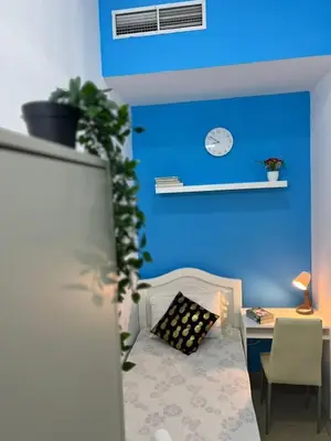 a bedroom with a blue wall with a bed and a desk at Smart Stay Partition Room In Barsha Heights Tecom in Dubai