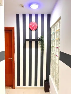 a hallway with a black and white striped wall with a clock at Smart Stay Partition Room In Barsha Heights Tecom in Dubai