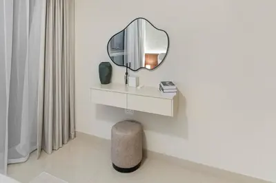 a mirror on a wall next to a stool in a bathroom at Luxury Apartment - Burj Khalifa, Creek - Best View in Dubai