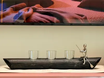 a small statue sitting on a table with three glasses at Mahenti - Stylish Urban Studio with Burj View in Dubai