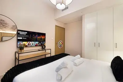 a bedroom with a white bed and a tv at Spacious 4BR for 12 Burj View PS5 Dubai Mall in Dubai