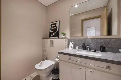 a bathroom with a toilet and a sink and a mirror at Spacious 4BR for 12 Burj View PS5 Dubai Mall in Dubai