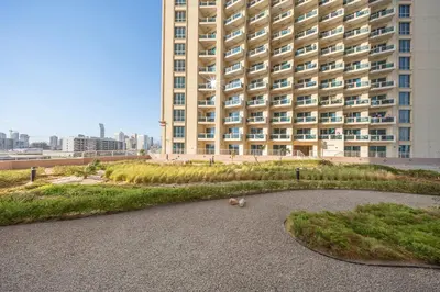 a building with a grassy area in front of a building at StayShort - Chic studio in Production City that sleeps 4 in Dubai