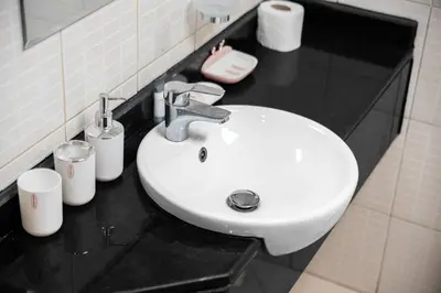a white sink in a bathroom with a black counter at StayShort - Chic studio in Production City that sleeps 4 in Dubai