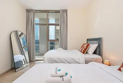 a bedroom with two beds and a mirror and a window at Bloomfields Spacious 2BR at Canal Bay in Dubai
