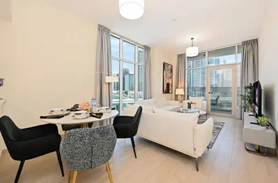 a living room with a white couch and a table and chairs at Bloomfields Spacious 2BR at Canal Bay in Dubai