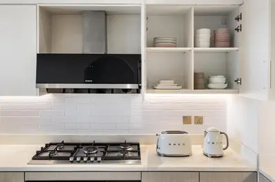 a kitchen with white cabinets and a stove top oven at Upscale 4BR Loft Duplex plus Maid in Creekside, Creek Harbour in Dubai