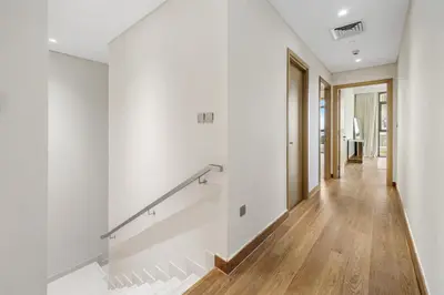 a hallway of a house with white walls and wood floors at Upscale 4BR Loft Duplex plus Maid in Creekside, Creek Harbour in Dubai