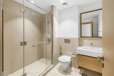 a bathroom with a shower and a toilet and a sink at Upscale 4BR Loft Duplex plus Maid in Creekside, Creek Harbour in Dubai