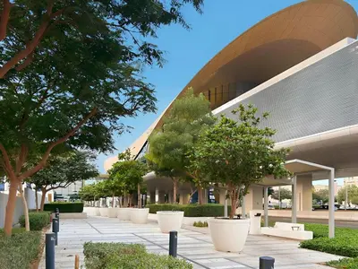a building with a bunch of trees in front of it at Brand New 1BR Near Metro at Avenue Residence in Dubai