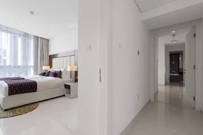 a white bedroom with a bed and a glass wall at Elegant 2BR Downtown Apartment - Near Burj Khalifa in Dubai
