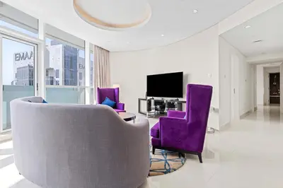a living room with purple chairs and a tv at Elegant 2BR Downtown Apartment - Near Burj Khalifa in Dubai