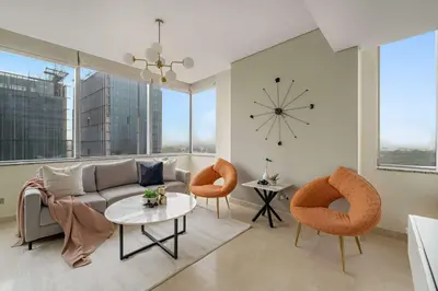 a living room with a couch and chairs and a clock at Silkhaus Expansive 2BDR in DIFC Sky Gardens in Dubai