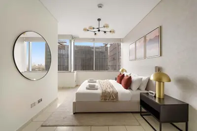 a white bedroom with a bed and a mirror at Silkhaus Expansive 2BDR in DIFC Sky Gardens in Dubai